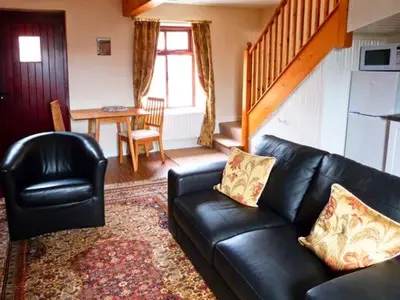 a living room with a black leather couch and a table at The Crook in Great Urswick