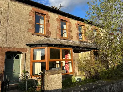 an old brick house with a large window at 2 West View in Holker