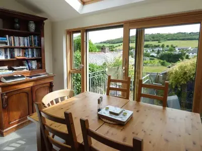 a dining room with a wooden table and a large window at 2 West View in Holker