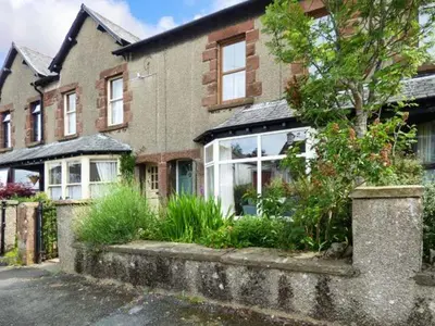 a brick house with a tree in front of it at 2 West View in Holker
