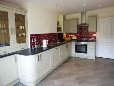 a large kitchen with white cabinets and black counter tops at 2 West View in Holker
