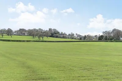 a large green field with trees in the distance at Pye Hall Cottage in Silverdale