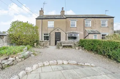 an old house with a bench in front of it at Pye Hall Cottage in Silverdale