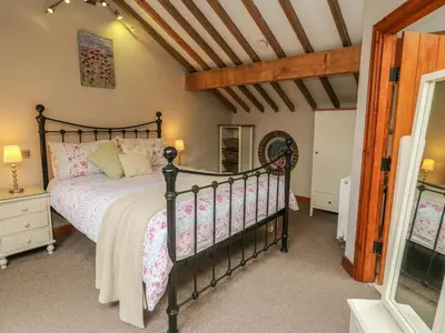 a bedroom with a black bed and a wooden ceiling at Barn Owl Cottage At Crook Hall Farm in Mawdesley