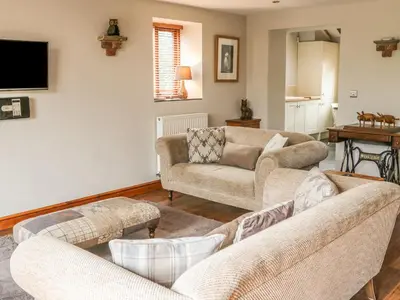 a living room with two couches and a tv at Barn Owl Cottage At Crook Hall Farm in Mawdesley