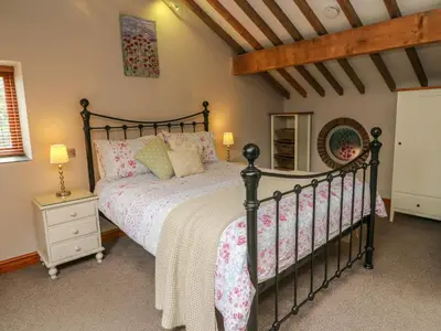 a bedroom with a black bed and a wooden ceiling at Barn Owl Cottage At Crook Hall Farm in Mawdesley