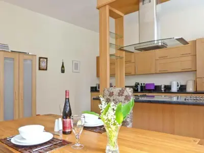 a kitchen with a wooden table with a bottle of wine at 2 Cark House in Holker