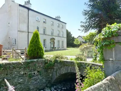 a stone bridge in front of a large building at 2 Cark House in Holker