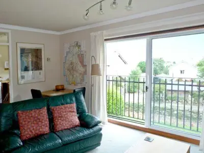 a living room with a green couch and a large window at Baytree Apartment in Grange Over Sands