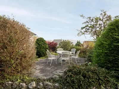 a patio with a table and chairs in a garden at Silverdale Mount in Grange Over Sands