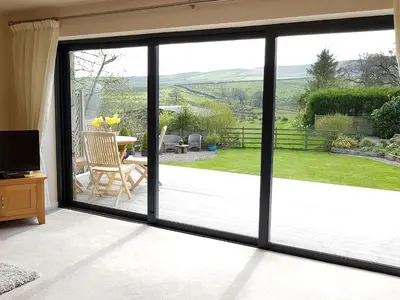 a sliding glass door with a view of a garden at Stone Mouse Cottage in Harrop Fold