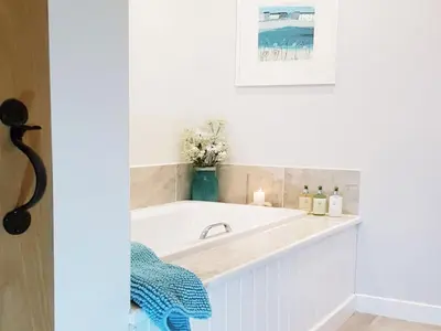 a bathroom with a bath tub with candles and flowers at Stone Mouse Cottage in Harrop Fold