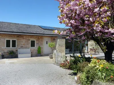 a house with a flowering tree in front of it at Stone Mouse Cottage in Harrop Fold