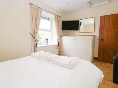 a bedroom with a white bed with towels on it at Fernleigh Cottage in Holker