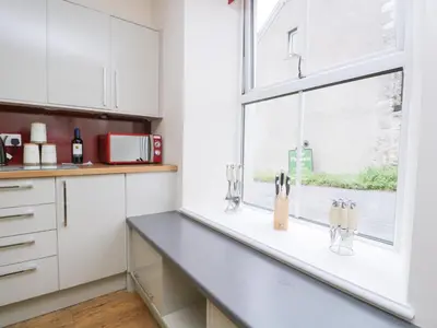 a kitchen with white cabinets and a window at Fernleigh Cottage in Holker