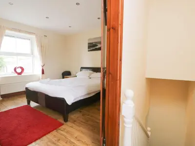 a bedroom with a bed and a red rug at Fernleigh Cottage in Holker
