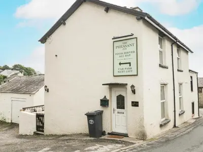 a white building with a sign on the side of it at Fernleigh Cottage in Holker