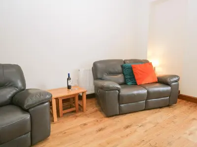 a living room with two leather chairs and a table at Fernleigh Cottage in Holker