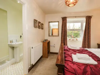 a bedroom with a bed and a sink and a mirror at 14 Low Row in Holker