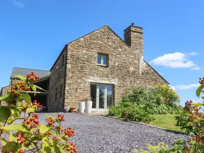 a stone house in the middle of a garden at Cottam Cottage Farm in Longridge