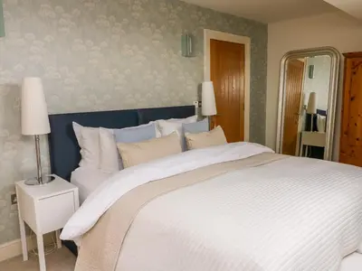 a bedroom with a large white bed and a mirror at Cottam Cottage Farm in Longridge