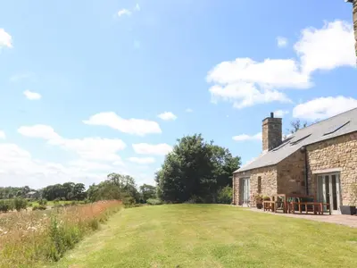 an old stone barn with a grassy yard next to it at Cottam Cottage Farm in Longridge