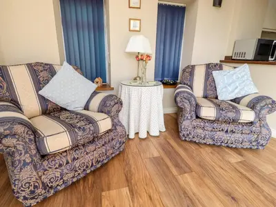 two chairs in a living room with blue curtains at Deekswood in Pilling