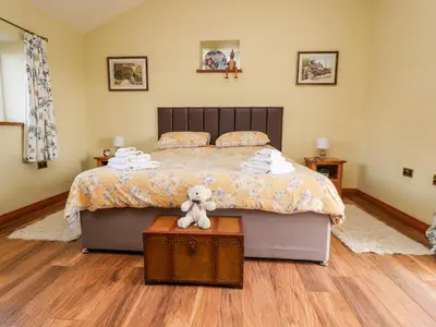 a bedroom with a bed with a teddy bear sitting on it at Deekswood in Pilling