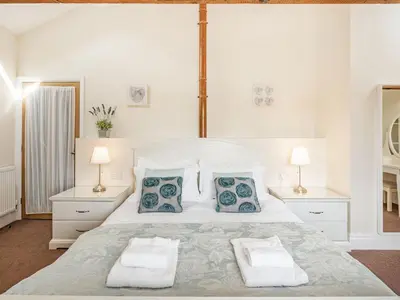 a white bedroom with a large bed with two pillows at Hay Barn in Burton in Lonsdale