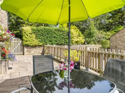 a table with a yellow umbrella on a patio at Hay Barn in Burton in Lonsdale