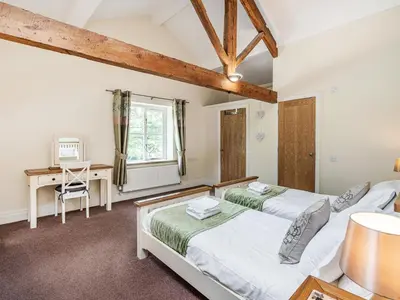 a bedroom with two beds and a desk at Hay Barn in Burton in Lonsdale