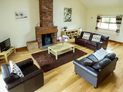 a living room with leather furniture and a fireplace at Parsley Cottage in Conder Green