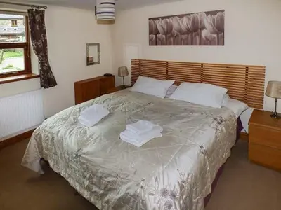 a bedroom with a large bed with towels on it at Parsley Cottage in Conder Green