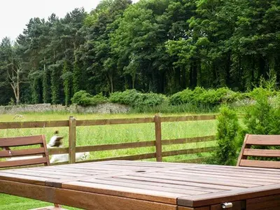 a wooden table with two benches next to a fence at Parsley Cottage in Conder Green