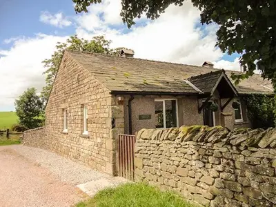 a small brick house with a stone wall at Bridleway Cottage in Wennington