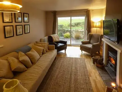 a living room with a large couch and a fireplace at Bridleway Cottage in Wennington