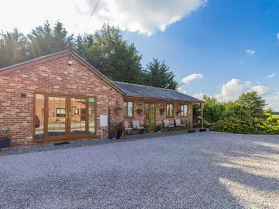 a brick house with a gravel driveway in front of it at Wild Duck Lodge in Rufford