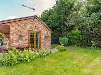 a small brick cottage with a garden at Wild Duck Lodge in Rufford