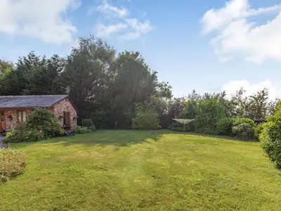 a yard with a brick house and a grass field at Wild Duck Lodge in Rufford