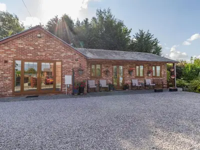 a brick house with chairs in front of it at Wild Duck Lodge in Rufford