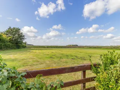 a large field of grass with a wooden fence at Wild Duck Lodge in Rufford