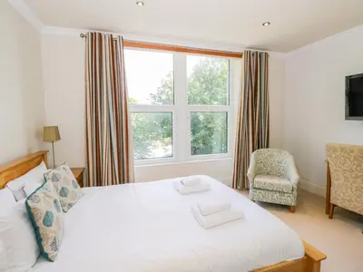 a bedroom with a bed and a window and a chair at Eden Lodge in Bardsea