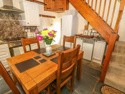 a kitchen with a wooden table with a vase of flowers at Horrace Farm Cottage in Pennington