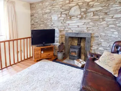 a living room with a stone wall with a television and a fireplace at Horrace Farm Cottage in Pennington