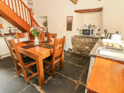a kitchen with a wooden table and chairs and a counter at Horrace Farm Cottage in Pennington