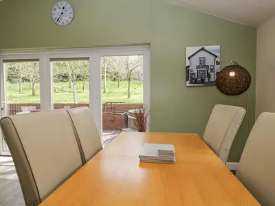 a dining room with a table and a clock on the wall at Cartmel Lodge in Cartmel