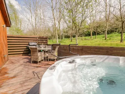 a jacuzzi tub on a deck with a table at Cartmel Lodge in Cartmel