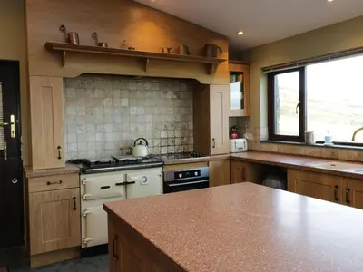 a kitchen with wooden cabinets and a counter top at Groffa Crag Farmhouse in Lowick Green