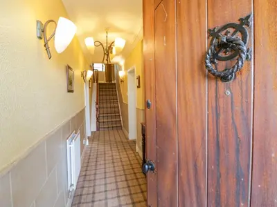 a hallway with a tile floor and stairs in a house at Groffa Crag Farmhouse in Lowick Green