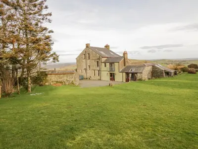 an old stone house with a green lawn at Groffa Crag Farmhouse in Lowick Green